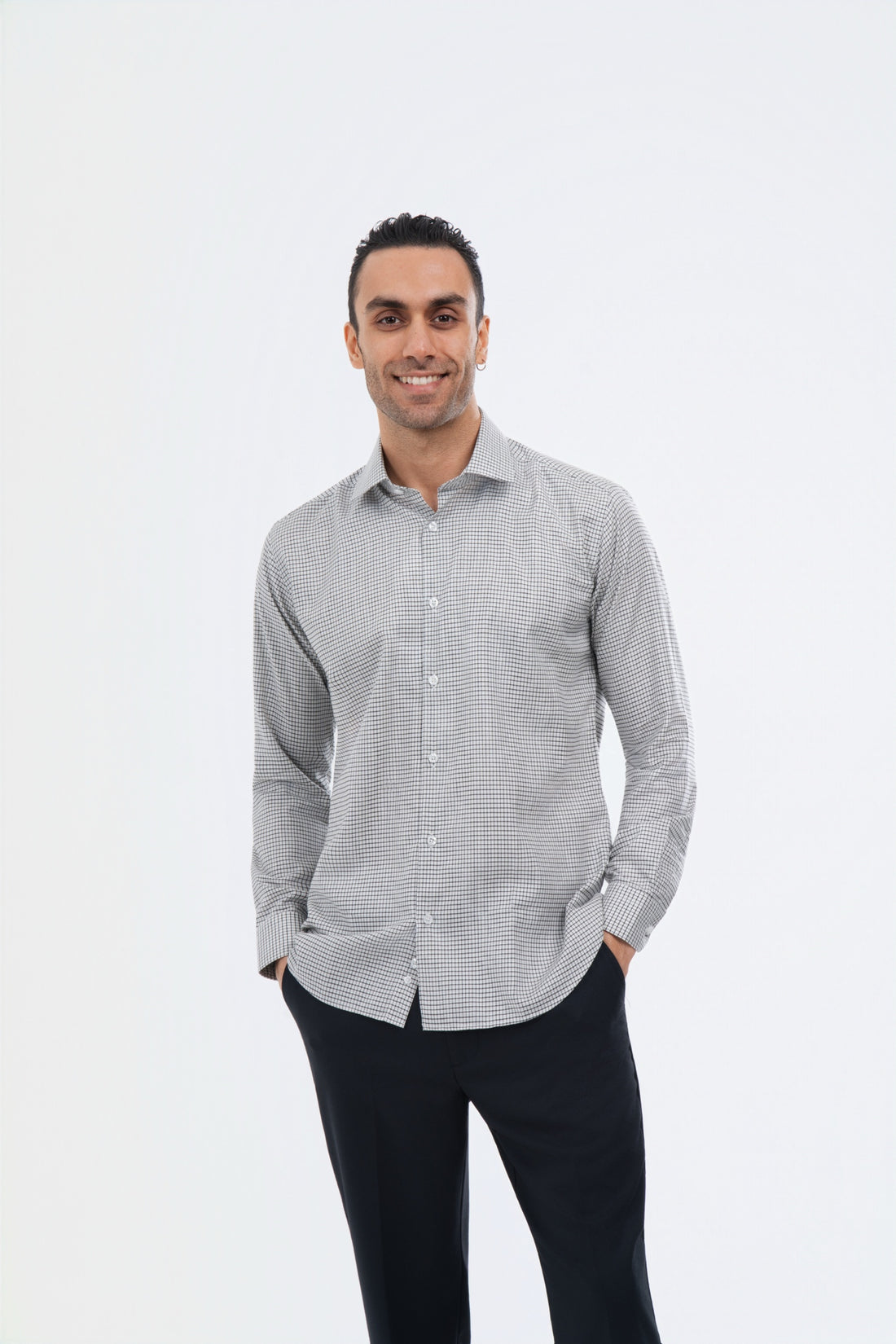 Male model wearing a grey micro-check shirt with black trousers in the studio.