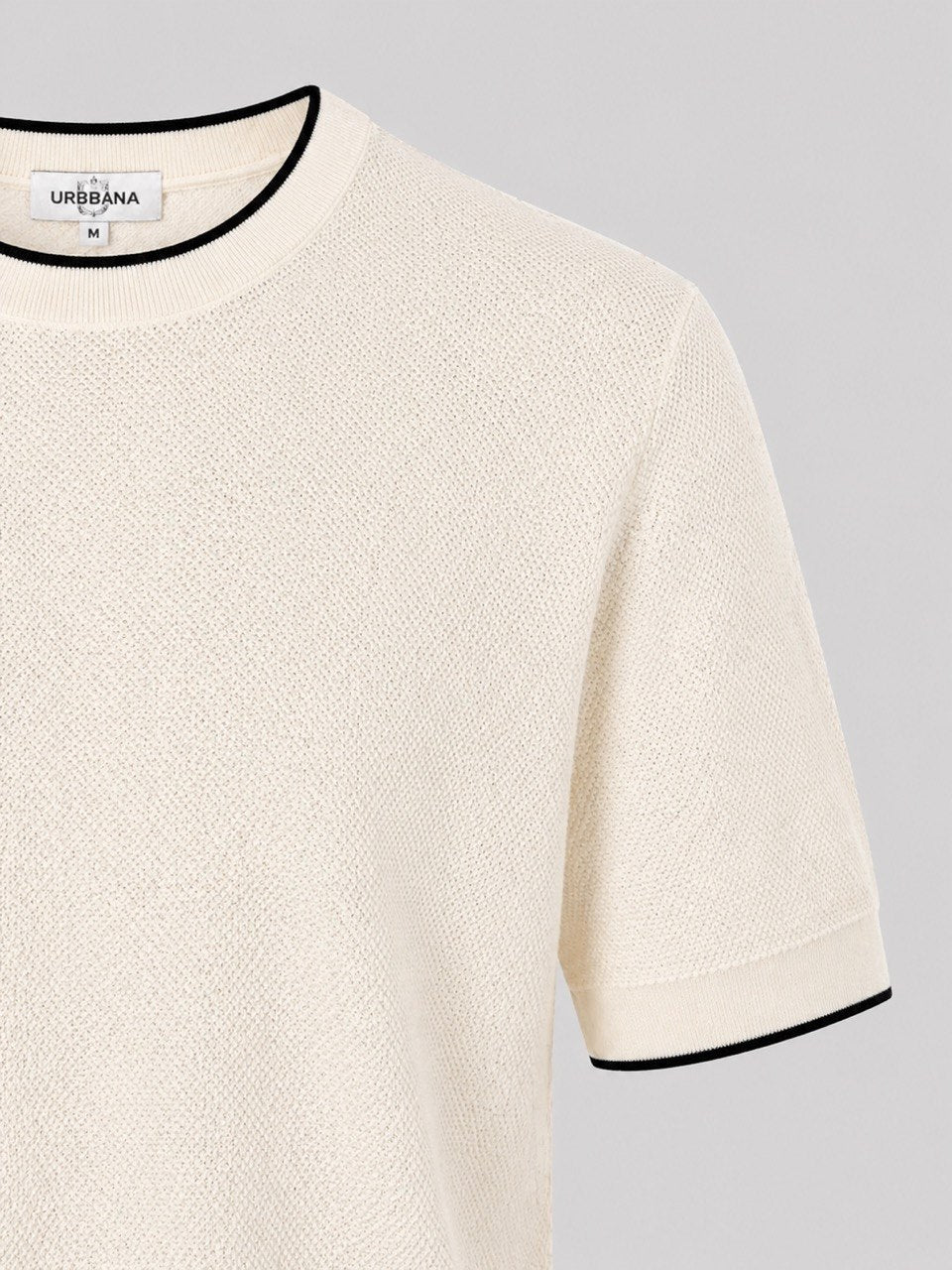 Close-up of a cream knitted crew-neck shirt with black trim.