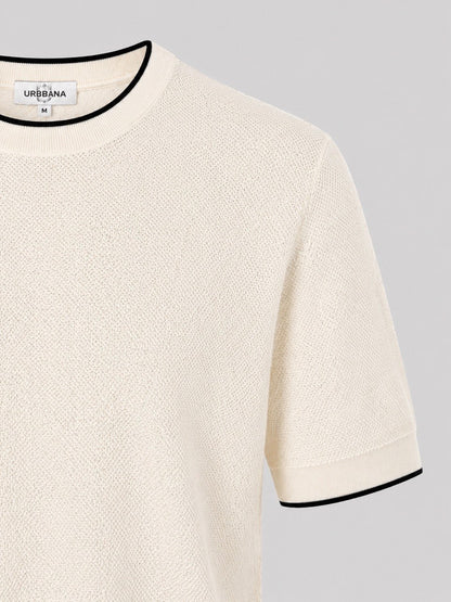 Close-up of a cream knitted crew-neck shirt with black trim.