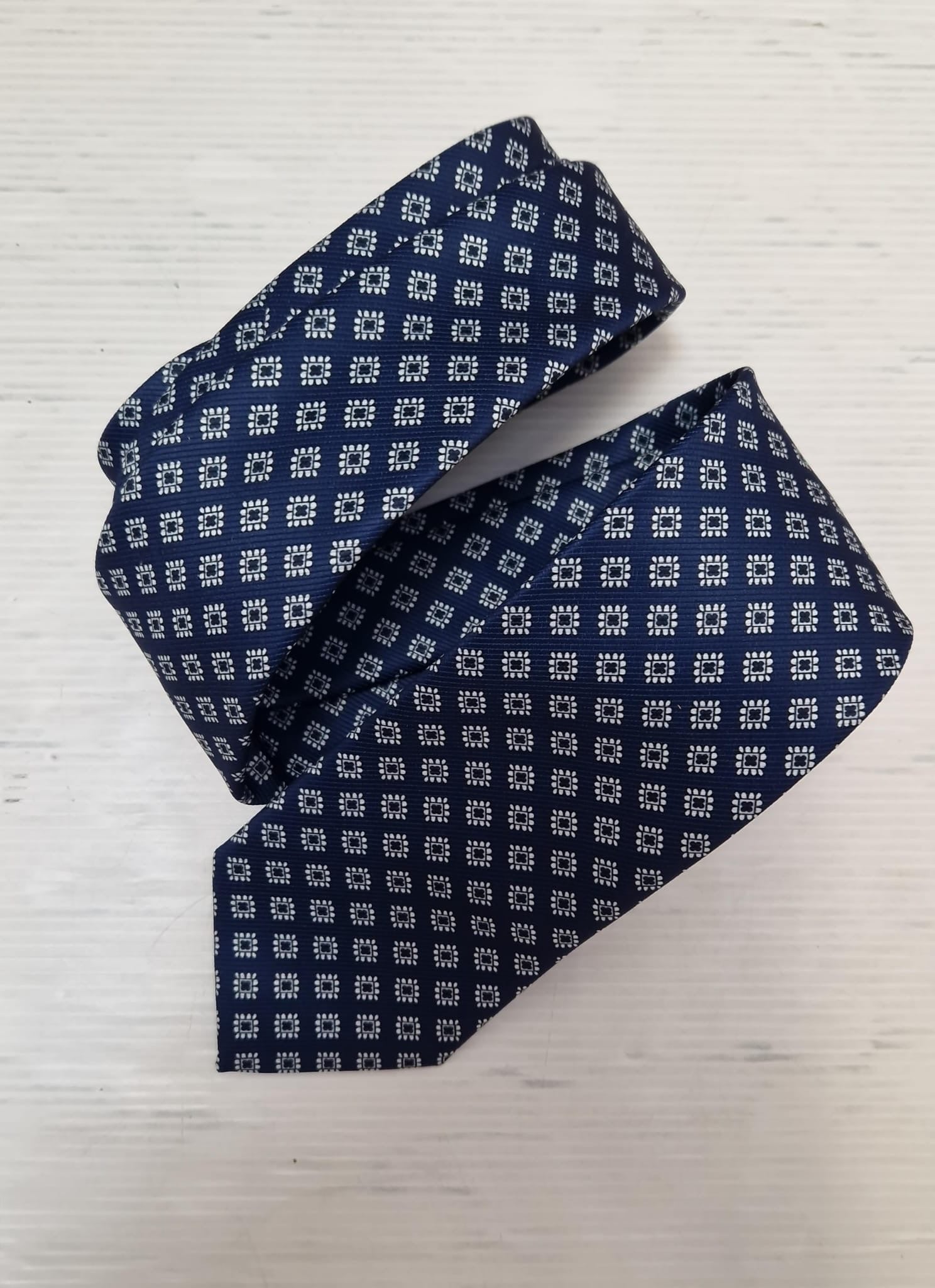 Navy silk tie with a light blue diamond pattern, loosely folded.
