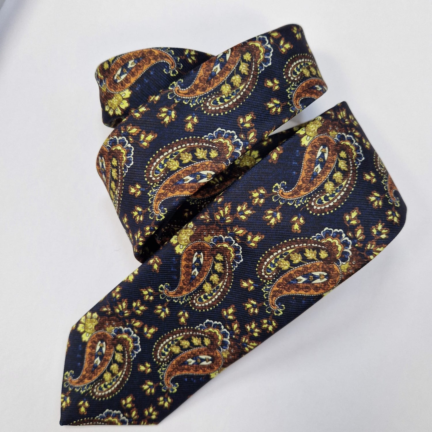 Navy, gold and olive paisley silk tie, loosely folded.