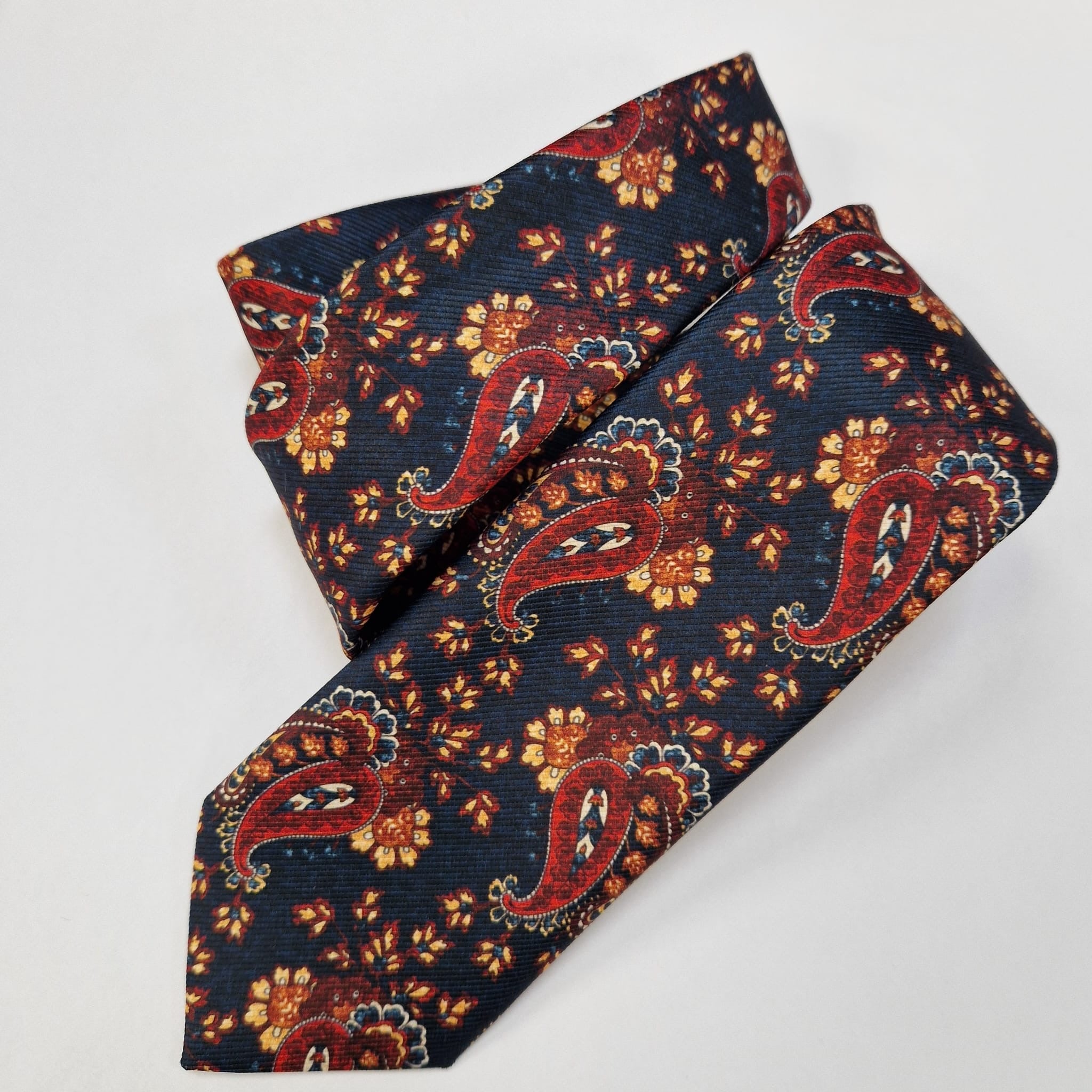 Navy and orange paisley silk tie, loosely folded.