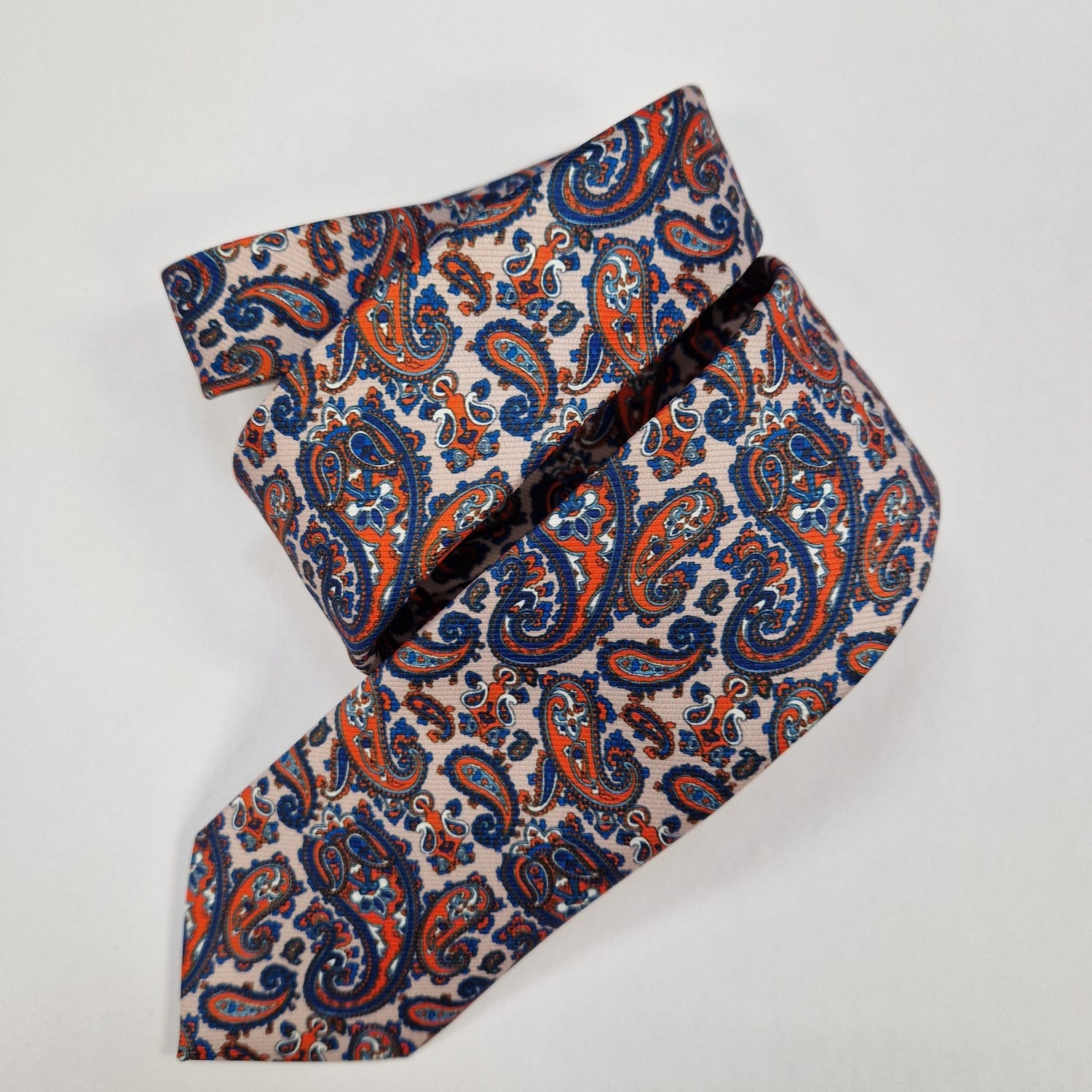 Navy silk tie with small silver paisley motifs, loosely folded.