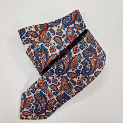 Navy silk tie with small silver paisley motifs, loosely folded.
