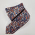 Navy silk tie with small silver paisley motifs, loosely folded.