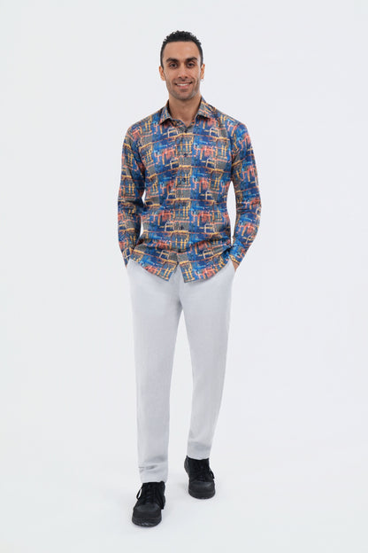 Male model wearing an orange and blue abstract-print shirt with white trousers.