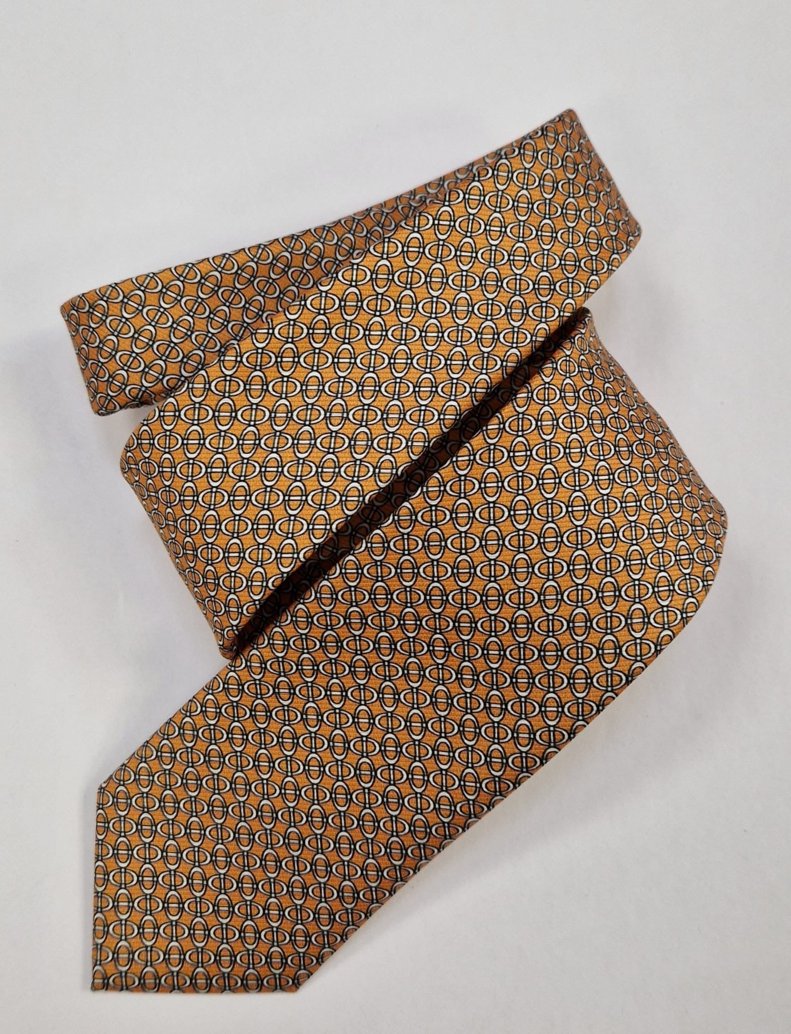 Orange and blue micro-geometric silk tie, loosely folded.