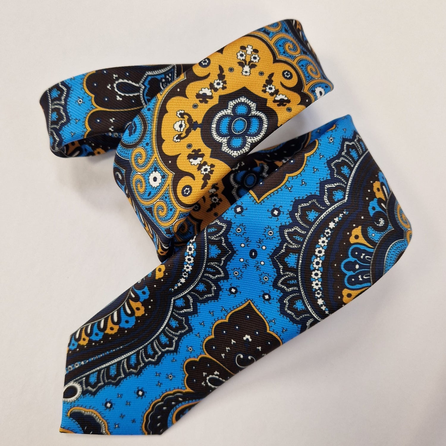 Turquoise and gold medallion paisley silk tie, loosely folded.